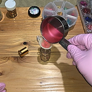 Pouring the lip oil mix via a funnel